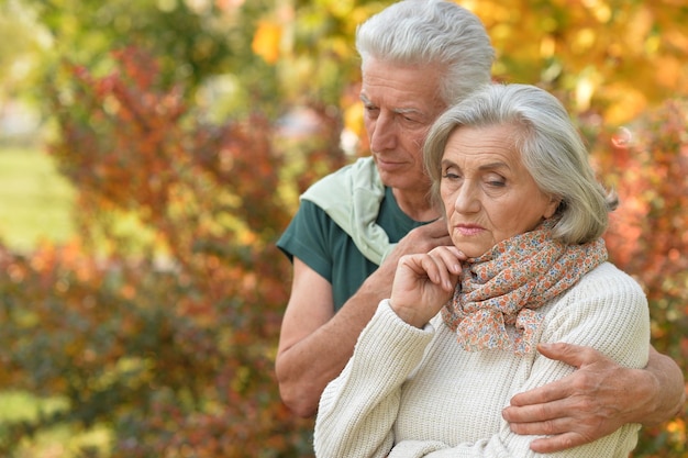 Portrait of cute sad senior couple in autumn park