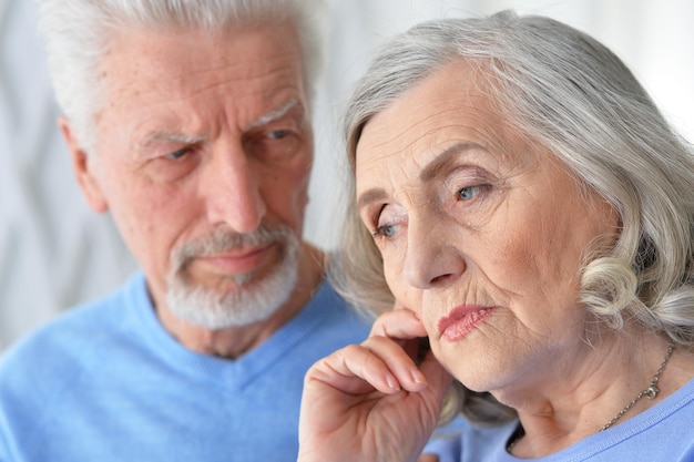 Portrait of cute sad senior couple posing at home