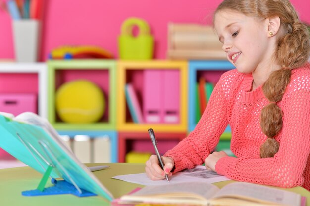 Portrait of cute schoolgirl doing homework at her room