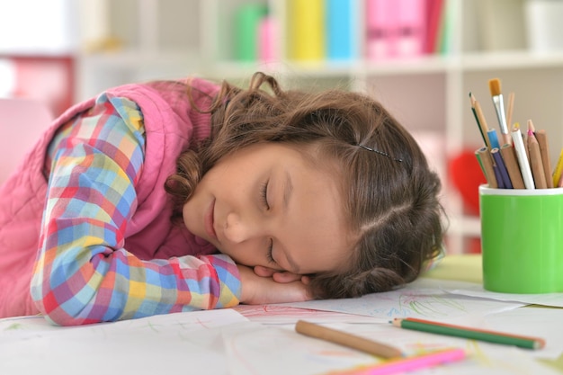 Portrait of cute schoolgirl sleeping on table