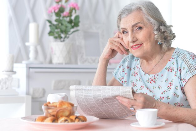 Portrait of cute senior woman with newspaper