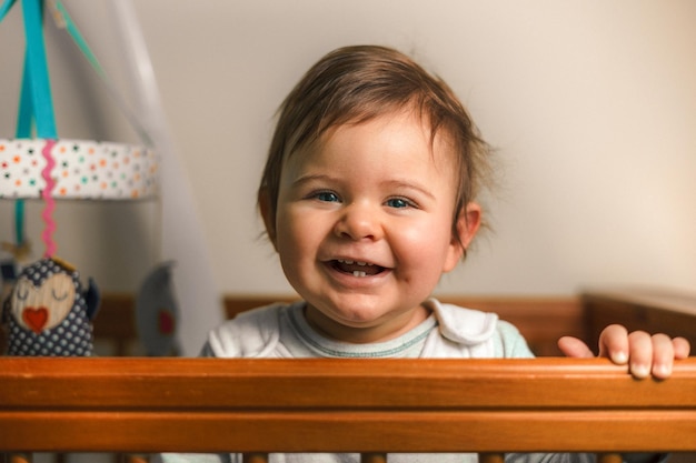 portrait of cute smiling baby boy in crib at home