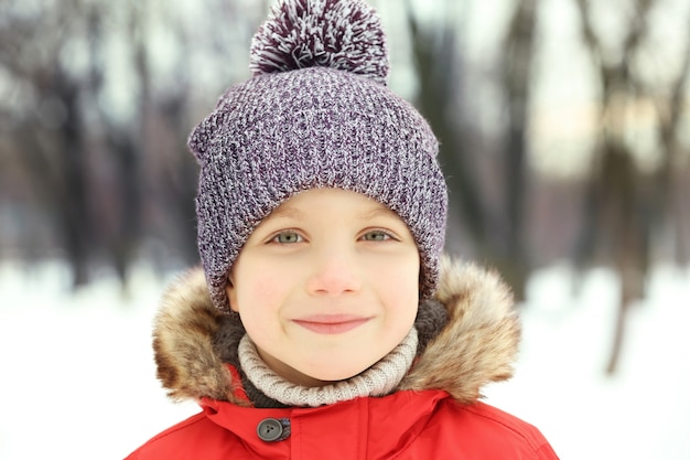 Portrait of cute smiling boy in beautiful warm outfit on winter background