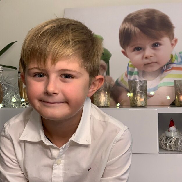 Foto ritratto di un ragazzo carino e sorridente seduto contro un poster