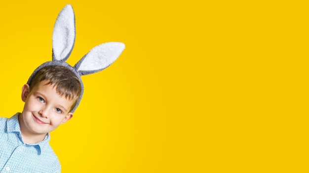 Portrait of cute smiling boy wearing Easter bunny ears on a yellow