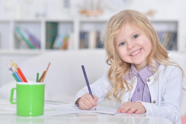 Portrait of cute smiling girl drawing at home