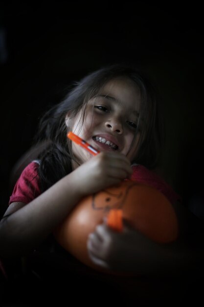 Foto ritratto di una ragazza sorridente con un palloncino sullo sfondo nero