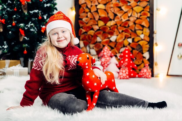 Portrait of cute smiling girl playing with toy while sitting on fur during christmas