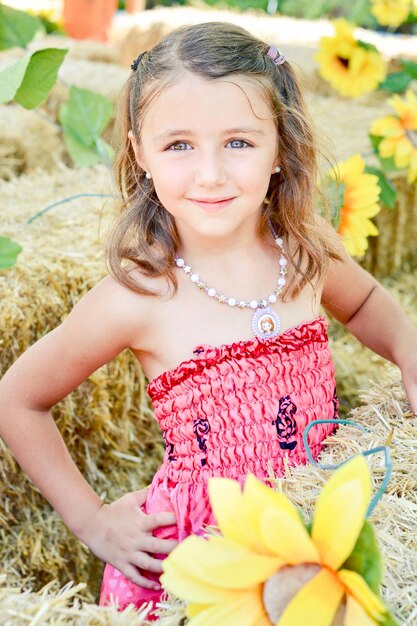 Photo portrait of cute smiling girl standing by hay bales