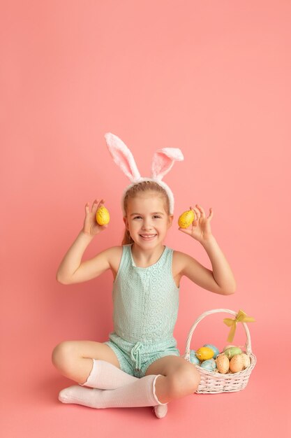 Portrait of cute smiling girl with Bunny ears and Easter basket isolated on pink background