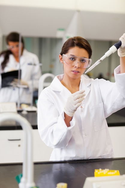 Portrait of a cute student pouring liquid in a tube