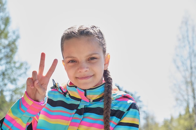 Photo portrait of a cute teenage girl on a background of spring greenery a girl with braids hairstyle loo