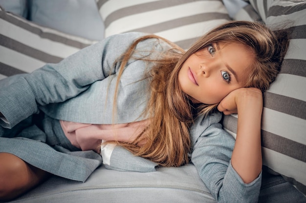 Portrait of a cute teenage girl lying on sofa in a living room.