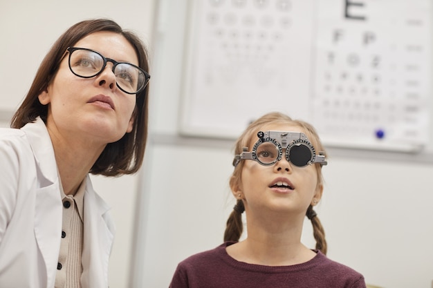 Portrait of cute teenage girl wearing trial frame during childs vision test