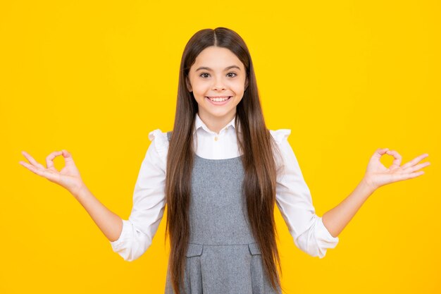 Portrait of cute teenager child girl pointing hand showing adverts with copy space over yellow background