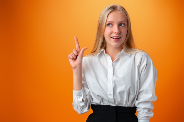 Portrait of cute thoughtful teen girl against orange background