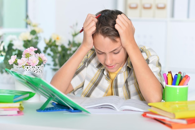 Photo portrait of a cute tired boy doing homework