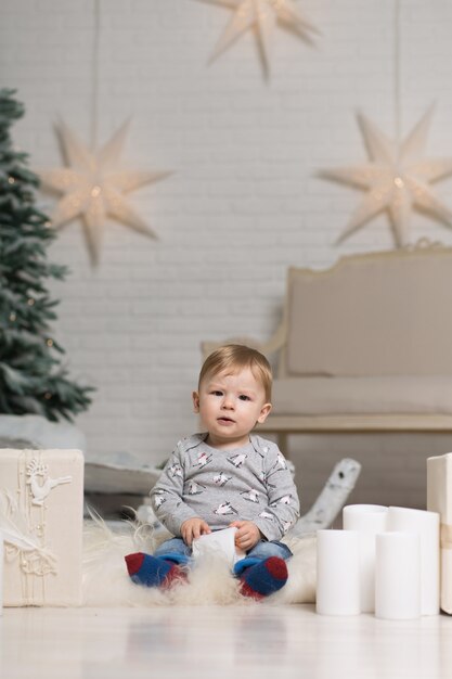 Portrait of a cute toddler playing on the floor near a Christmas tree. Merry Christmas and happy holidays.