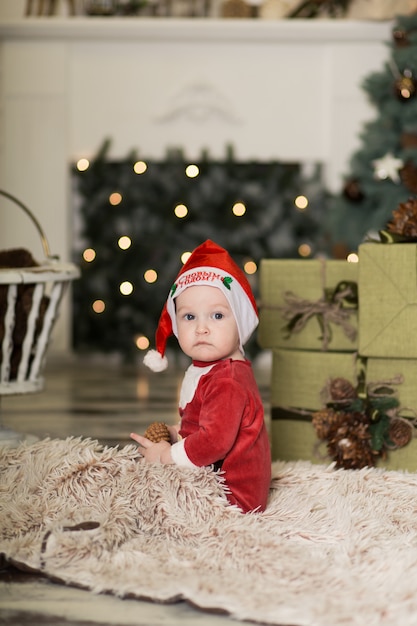 クリスマスツリーを飾るためにコーンで床で遊ぶかわいい幼児の肖像画。