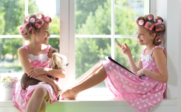 Portrait of cute tweenie girls with hair curlers sitting