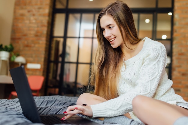 Il ritratto di una donna carina trascorre un bel fine settimana in un appartamento di lusso con il suo laptop.