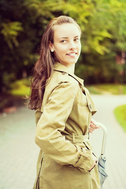 Portrait of a cute woman in the jacket walks through the autumnal park.