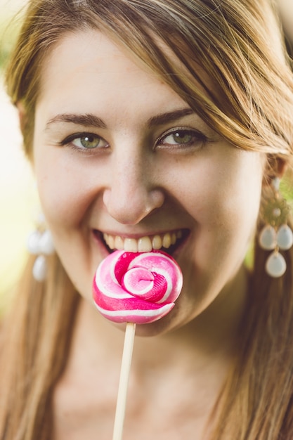 Portrait of cute woman licking red twisted lollipop