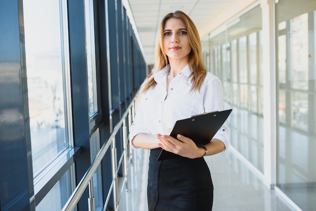 Portrait of a cute young business woman smiling, in an office environment