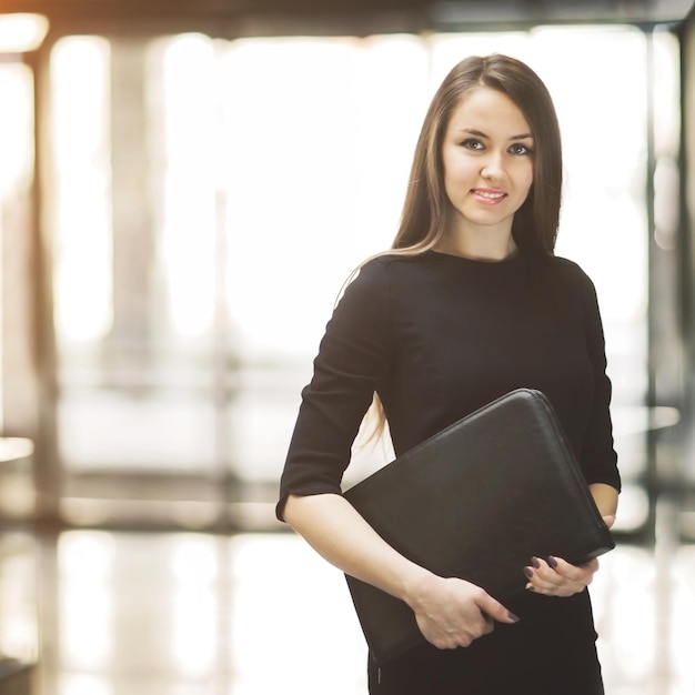 Portrait of cute young business woman smiling in the office the hands of the folder