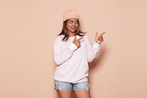 portrait of cute young girl happily posing to show something in solid background