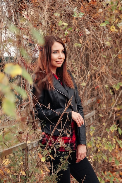Portrait of cute young woman of Slavic appearance in casual wear in autumn, on countryside against background of an autumn Park. Pretty female walking in forest in golden fall. Copy space
