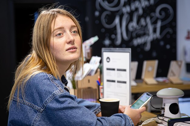 Foto ritratto di una giovane donna carina con un telefono e un caffè