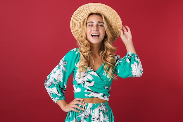 Portrait of cutie laughing smiling young beautiful blonde cute woman in dress posing isolated over red wall