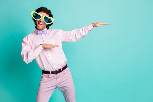 Portrait of dancing guy dressed formalwear bow heart shaped summer glasses isolated on turquoise color background