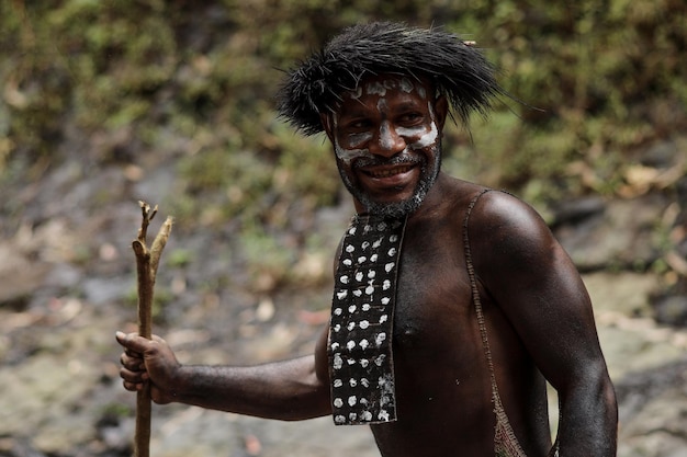 Ritratto dell'uomo della tribù dani della papua indonesia che indossa kotekais sorride mentre porta cibo dalla caccia