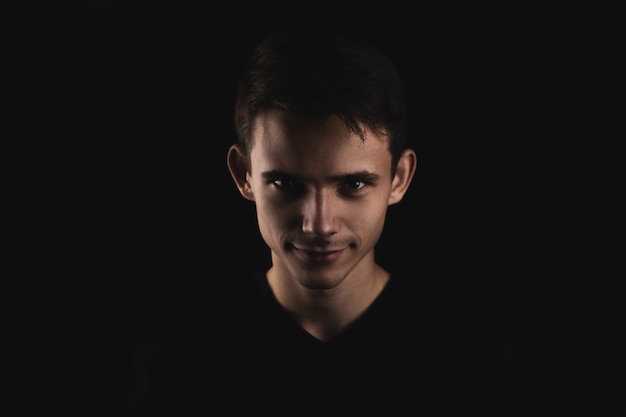 Portrait of a dark-haired young man on a black background.