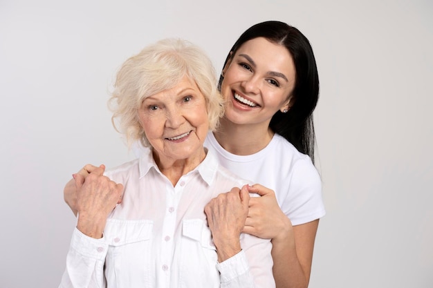 Portrait of daughter embracing her smiling mother isolated white colour background People posing together Family concept