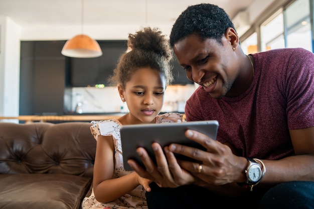 Portrait of a daughter and father using a digital tablet while staying at home