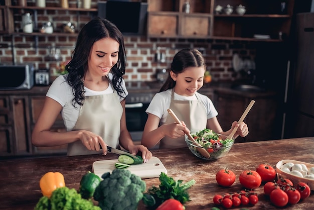 Портрет дочери и матери вместе готовят свежий салат на кухне