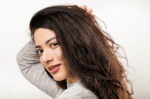 Portrait of delighted, shy brunette girl with long hair. Young emotional lady with friendly facial expression, smiling.