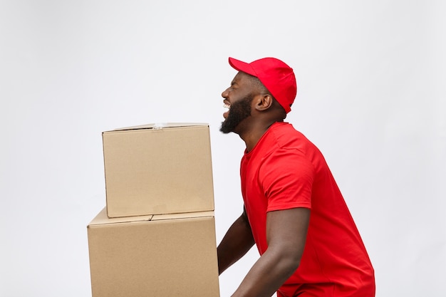 Portrait of delivery african american man in red shirt. he lifting heavy weight boxes