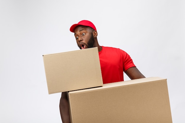 Portrait of delivery african american man in red shirt. he lifting heavy weight boxes