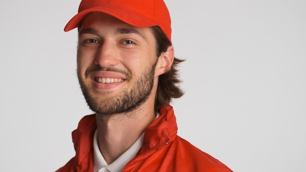 Portrait of delivery man wearing red cap looking confident at camera over white background