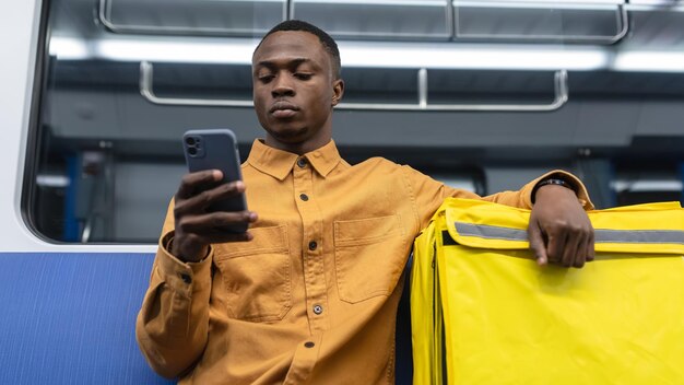 Portrait of a delivery man who spends time on the phone Professional courier service Delivery man in the subway