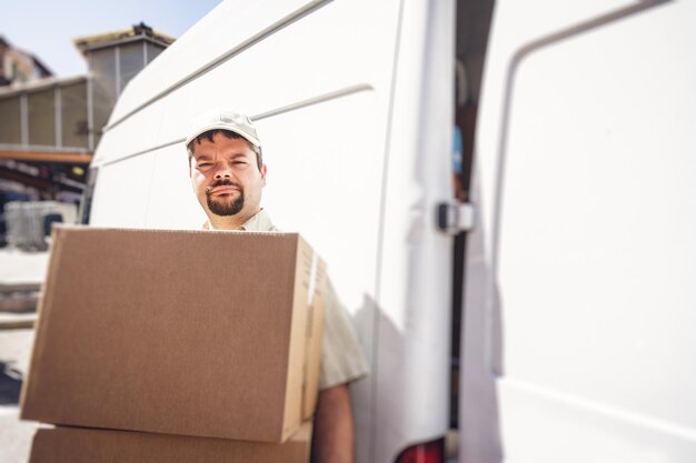 Photo portrait of delivery man with cardboard boxes standing by van