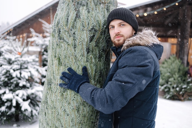 エコの木モミの木のクリスマス ツリー グリーン ショップ市場のそばに立つ配達員の肖像画