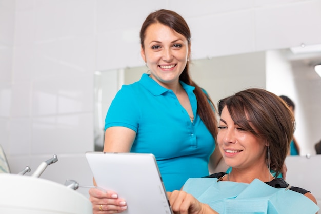 Photo portrait of a dentist discussing a treatment plan with a patient on a tablet