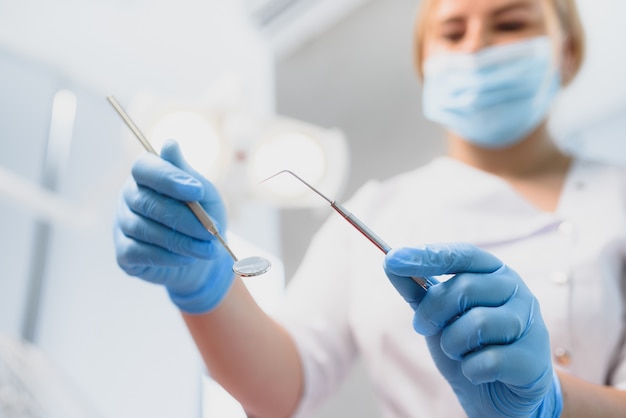 Photo portrait of a dentist holding dental instruments in his hands in the clinic close-up