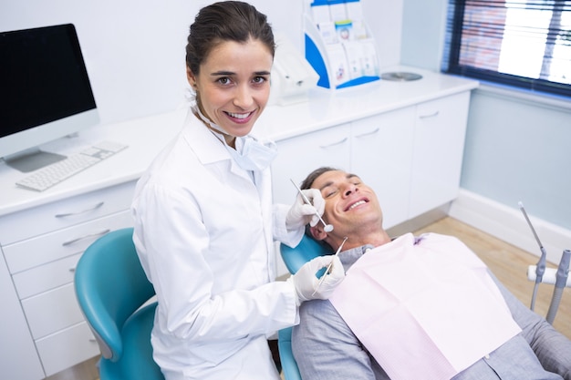 Portrait of dentist holding equipment while standing by patient