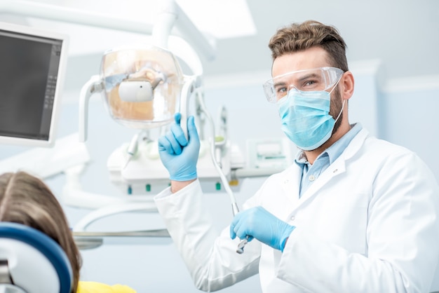 Ritratto di un dentista in maschera e occhiali protettivi durante la chirurgia dentale